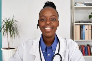African female doctor wear headset make webcam zoom video call, face headshot.
