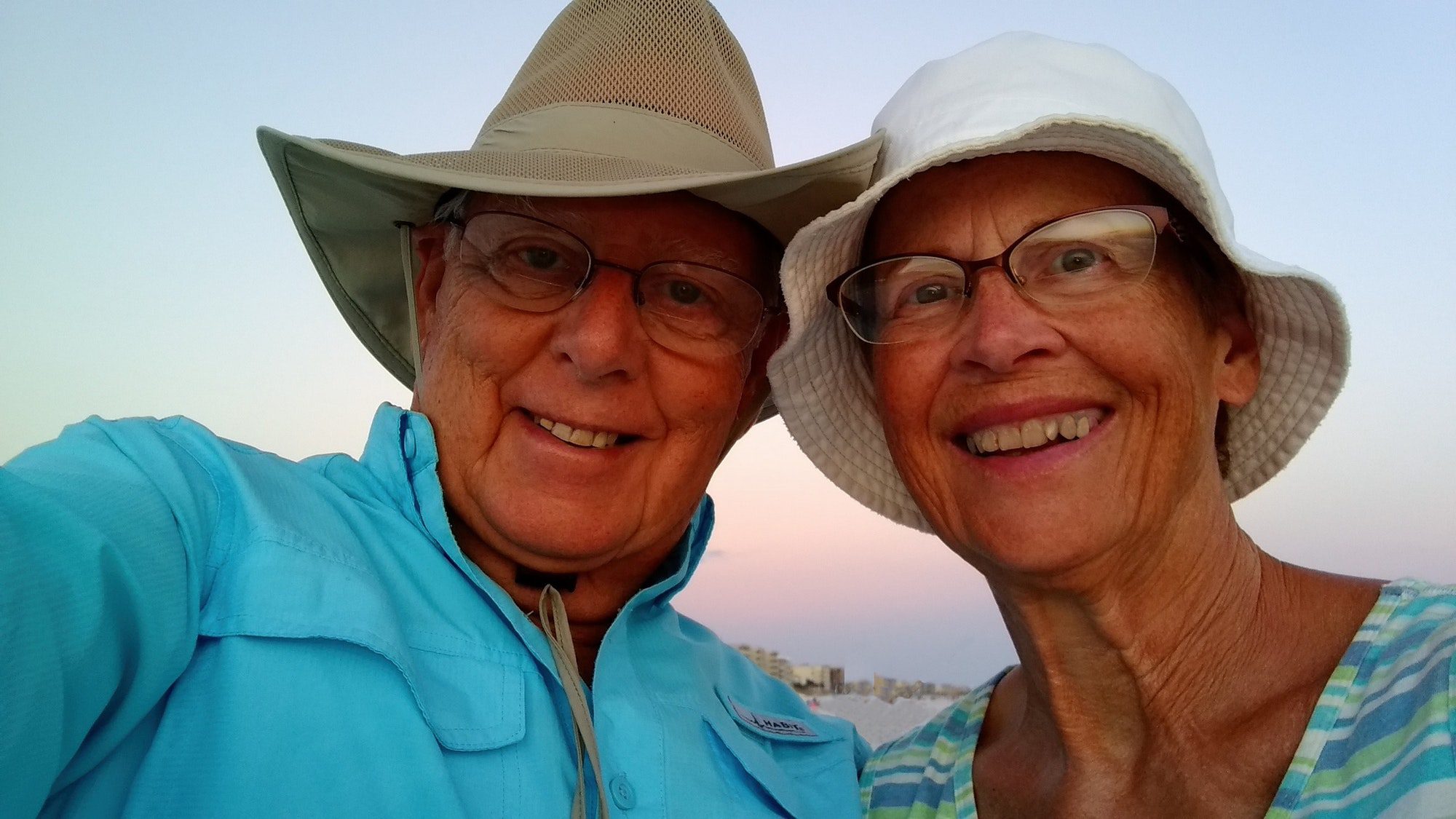 Seniors on the beach with big smiles happily enjoying a vacation as the sun