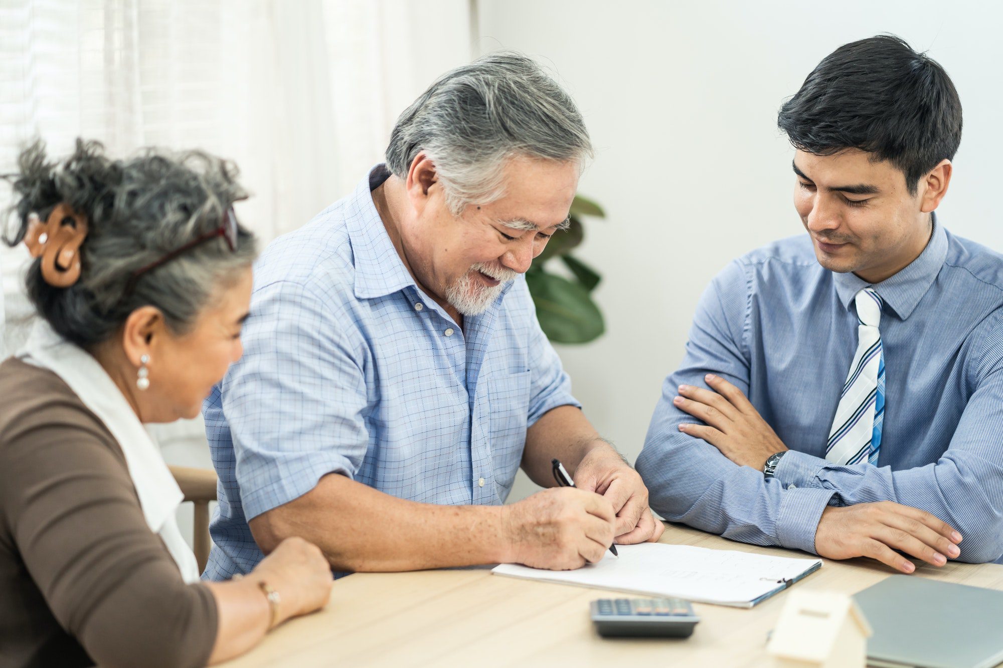 Asian couple senior elder chooses the right Medicare option at a table with broker visit at home.