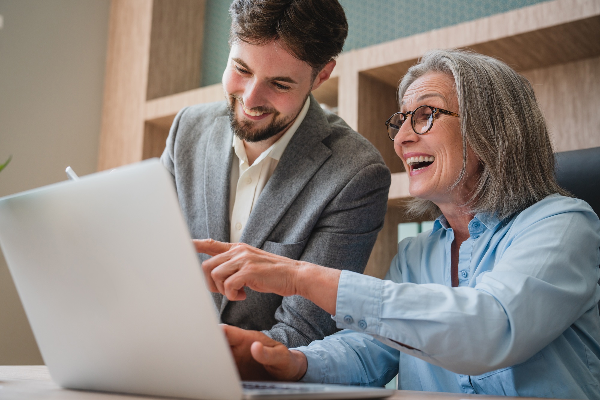 Senior Woman and Young Man Collaborating on a Laptop at Office Desk